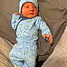 baby, infant, blue_outfit, dinosaur_pattern, hat, footed_pajamas, cute, lying_down, soft_surface, newborn, child, clothing, sleepwear, cozy, small_hands, portrait, indoors, person, face, headwear