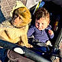 baby, monkey, stroller, animal, child, outdoor, sunlight, leash, curious, pavement, young_child, face, portrait, seat, clothing, hair, hand, expression, daylight, pet