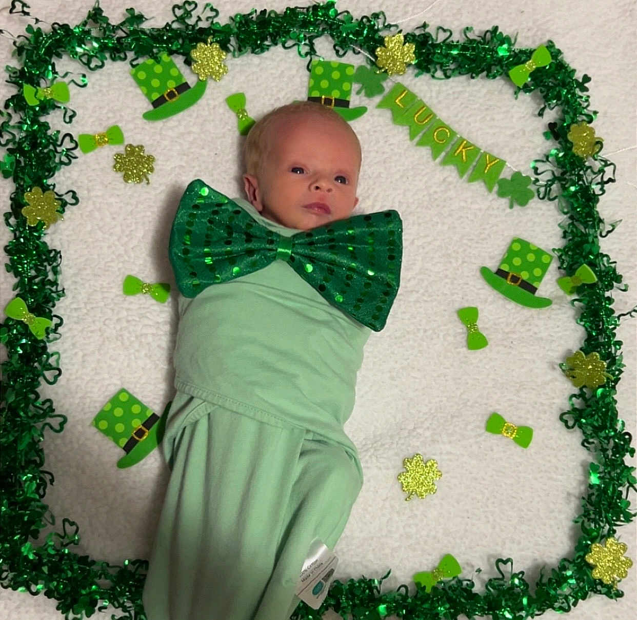 Nolan Keith is registered to the contest to win money with this photo: baby, infant, newborn, bow_tie, green_decor, st_patricks, shamrock, leprechaun_hat, garland, swaddle, blanket, portrait, lying_down, festive, holiday, cute, decoration, eyes_open, face, adorable