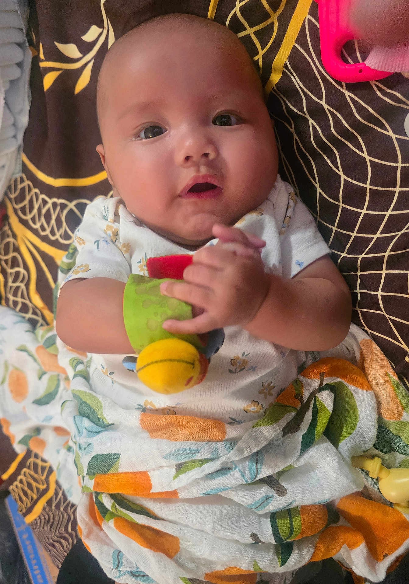 Avery is registered to the contest to win money with this photo: baby, infant, toy, blanket, clothing, face, hand, pattern, colorful, curious, child, cute, indoor, portrait, expression, skin, resting, fabric, playful, young