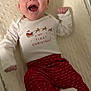 Emeri is registered to the contest to win money with this photo: baby, infant, smiling, happy, christmas, holiday, festive, pajamas, red_pants, white_shirt, santa_claus, reindeer, blanket, soft, cozy, cute, lying_down, indoors, celebration, cheerful