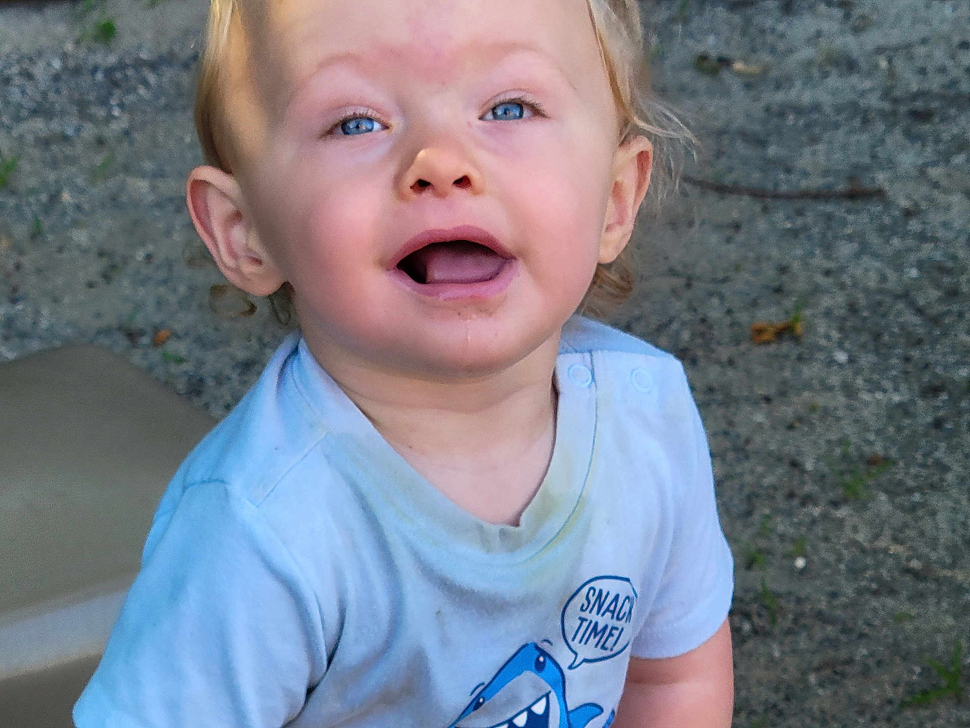 Able is registered to the contest to win money with this photo: toddler, child, blue_eyes, open_mouth, shirt, graphic_tee, shark, outdoor, gravel, dirt, happy, messy_face, short_hair, light_blue, playful, cute, person, young_child, casual_clothing, daylight