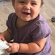 Violet is registered to the contest to win money with this photo: baby, child, smiling, purple_shirt, black_pants, puma_logo, sitting, floor, wooden_floor, toy, diaper, happy, indoor, cute, chubby_arms, short_hair, playtime, person, infant, casual_clothing