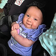 Emerie is registered to the contest to win money with this photo: baby, infant, car_seat, child, smiling, purple_clothing, headband, blanket, seatbelt, cute, portrait, indoor, sitting, happy, person, baby_girl, soft_texture, closeup, young_child, wearing_clothes