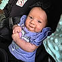 baby, infant, car_seat, child, smiling, purple_clothing, headband, blanket, seatbelt, cute, portrait, indoor, sitting, happy, person, baby_girl, soft_texture, closeup, young_child, wearing_clothes