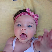 Nina participe au concours pour gagner de l'argent avec cette photo : arm, baby, blue_background, child, closeup, cushion, cute, expression, face, headband, indoor, infant, person, photography, playful, red_checkered, skin, tongue, white_tank_top, yellow