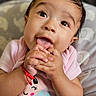 baby, background_blur, bracelet, child, close_up, cute, eyes, face, fingers, flower_design, hands, happy, indoors, infant, pink_shirt, playful, portrait, skin, smiling, soft_light