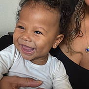 Kaïzen a rejoint le concours — aidez-le/la à gagner de superbes lots ! baby, child, smiling, curly_hair, white_clothing, person, hand, indoor, portrait, happy, adult_hand, jewelry, necklace, skin, face, holding, cute, infant, closeup, love