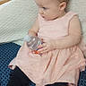 baby, black_leggings, blue, child, curious, cute, dress, holding_object, indoor, infant, light_skin, patterned_cushion, pink, portrait, short_hair, side_profile, sitting, soft_fabric, water_bottle, young_child