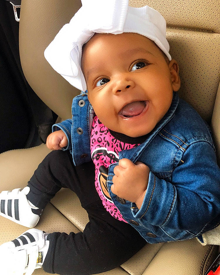 Oakley is registered to the contest to win money with this photo: baby, baby_toddler_clothing, cap, cheek, child, comfort, cool, electric_blue, fashion_accessory, finger, gesture, happy, headgear, headwear, outerwear, person, sitting, skin, sleeve, smile