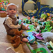 Simon is registered to the contest to win money with this photo: brown_overalls, carpet, child, cubby_house, curtain, face, floor, indoor, light, party_hat, person, play_mat, plush_toy, room, striped_shirt, stuffed_animal, tent, toddler, toy, window