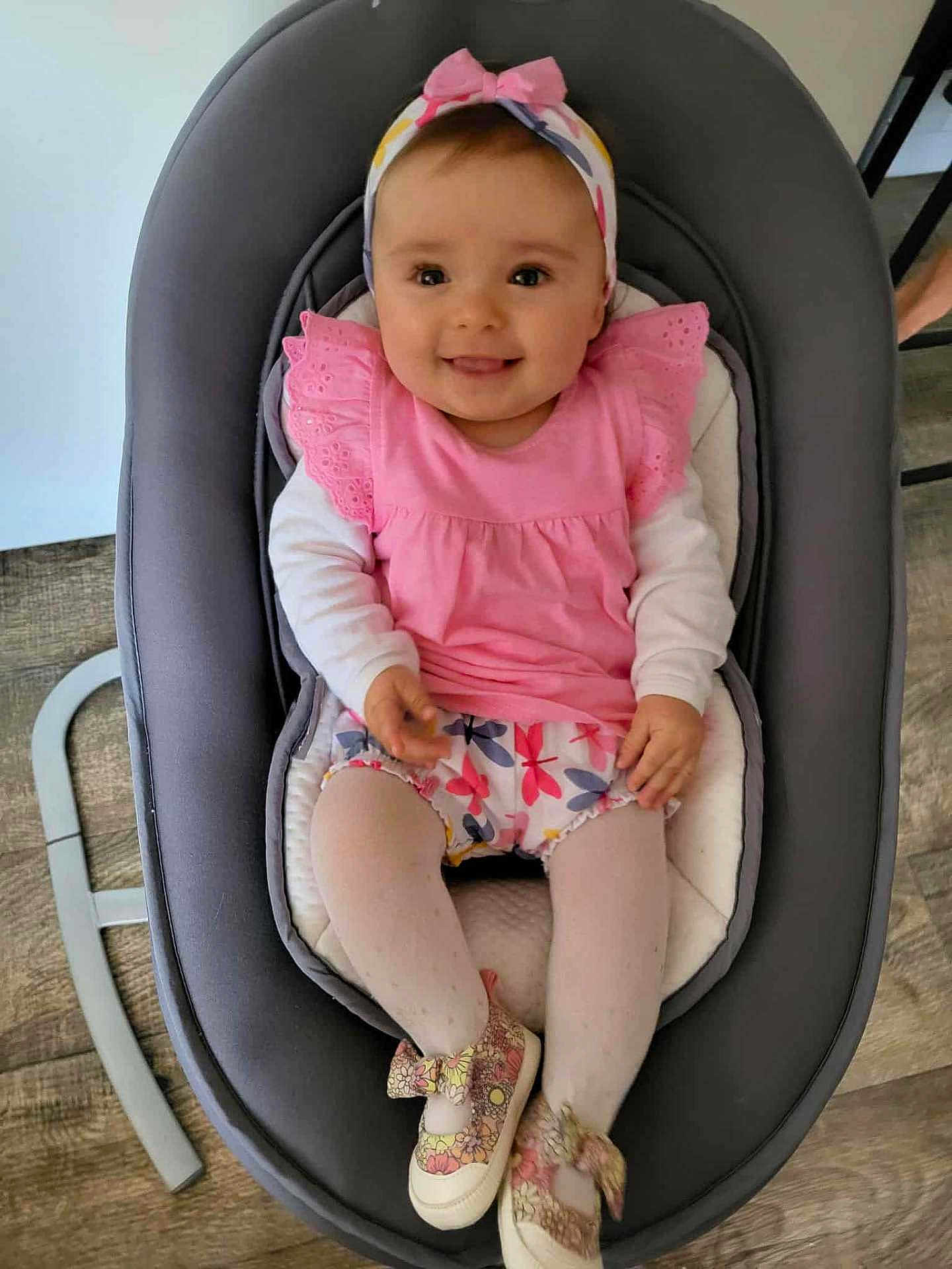 Lily a rejoint le concours — aidez-le/la à gagner de superbes lots ! baby, infant, smiling, pink_clothing, headband, baby_rocker, shoes, tights, child, cute, happy, indoor, flooring, wood_floor, seat, person, portrait, playful, home, young_child