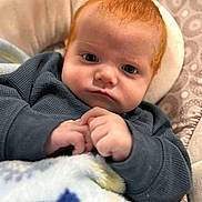 Hayden Roker is registered to the contest to win money with this photo: baby, redhead, infant, face, hands, blanket, clothing, sweater, cushion, pattern, portrait, indoor, child, young, closeup, resting, expression, cozy, cute, skin