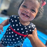 Syla is registered to the contest to win money with this photo: baby, bright, child, closeup, curly_hair, hair_bow, hand, happy, outdoor, person, playful, polka_dot_dress, pool, red_belt, skin, smiling, summer, toddler, water, wet_face