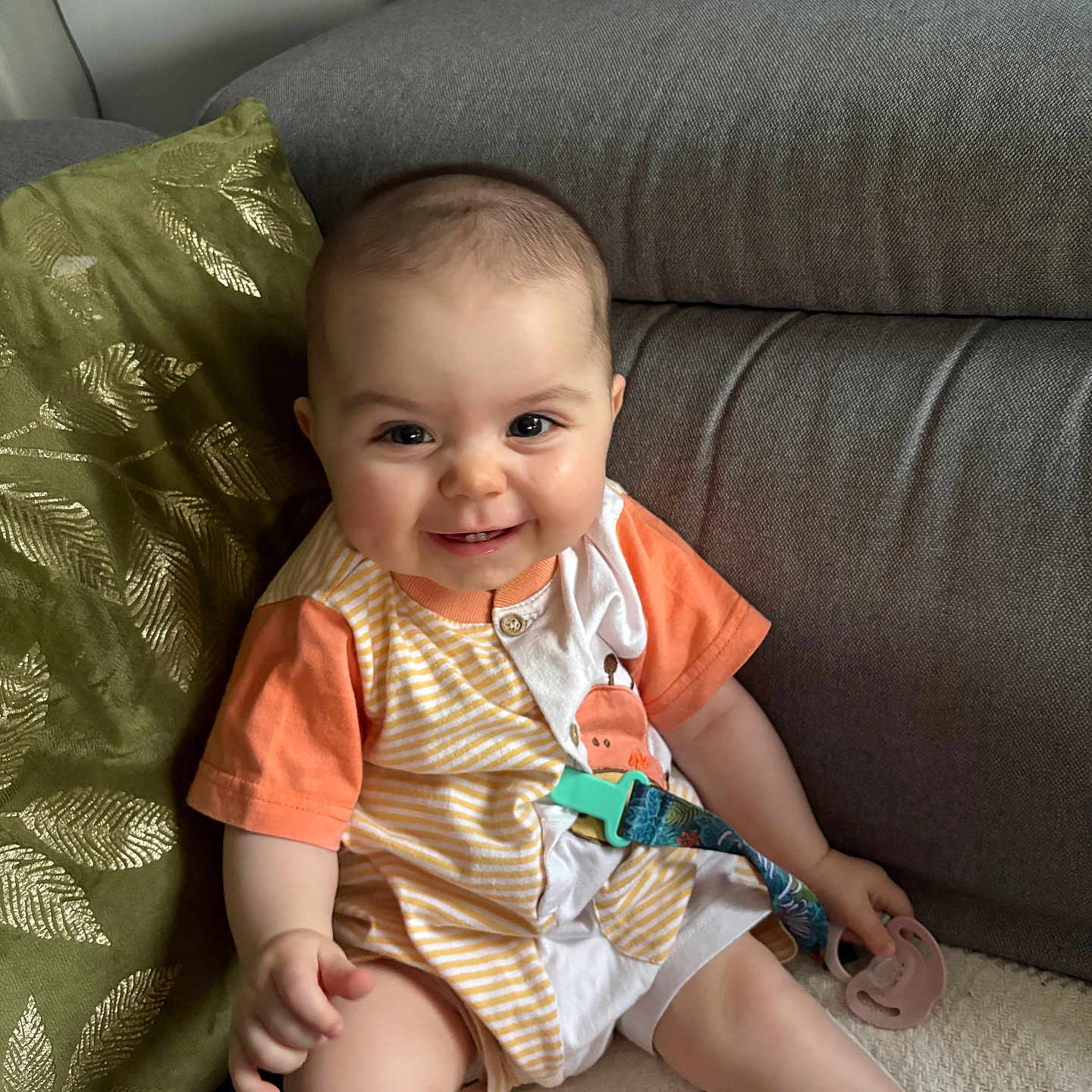 Moéa participe au concours pour gagner de l'argent avec cette photo : apparel, baby, child, clothing, comfort, couch, cute, face, happy, home, indoor, infant, pacifier, person, pillow, portrait, relaxing, sitting, smiling, young