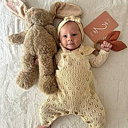 Adelia participe au concours pour gagner de l'argent avec cette photo : baby, infant, knitted_clothing, headband, stuffed_animal, bunny, toy, milestone_card, blanket, soft_texture, lying_down, hand, foot, cute, smile, face, child, indoor, portrait, laying
