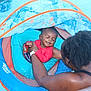 Auguste is registered to the contest to win money with this photo: baby, child, pool, water, floaty, smiling, adult, swimming, fun, summer, outdoor, person, happy, blue, red, skin, hair, relaxation, vacation, safety