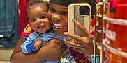 Auguste is registered to the contest to win money with this photo: baby, adult, mirror, bathroom, selfie, smiling, pajamas, toiletries, towels, sink, phone, reflection, happy, person, holding, child, clothing, face, indoor, family