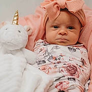 Emery joined the competition — help win amazing prizes! baby, infant, headband, bow, pink, floral_outfit, plush_toy, unicorn, blanket, soft_toy, cute, portrait, indoors, child, face, expression, newborn, cozy, resting, person