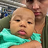 Gina is registered to the contest to win money with this photo: baby, woman, person, child, clothing, face, portrait, indoor, retail_store, shopping, denim, green_clothing, holding, closeup, head_and_shoulders, casual, expressionless, adult, store, people