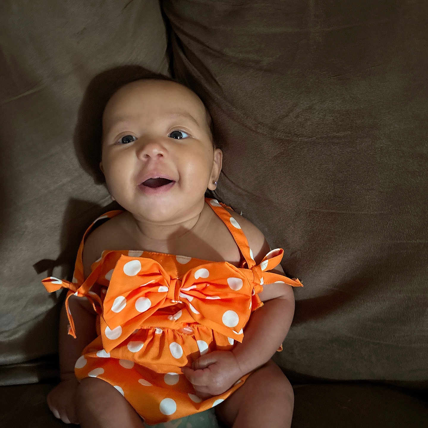Gina joined the competition — help win amazing prizes! baby, child, infant, orange_dress, polka_dot, bow, smiling, happy, sitting, couch, furniture, indoor, cute, portrait, skin, face, eyes, mouth, hands, legs