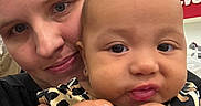 Gina is registered to the contest to win money with this photo: baby, woman, face, portrait, closeup, indoor, store, retail, leopard_print, clothing, holding, child, person, head, skin, expression, shopping, hair, eyes, casual
