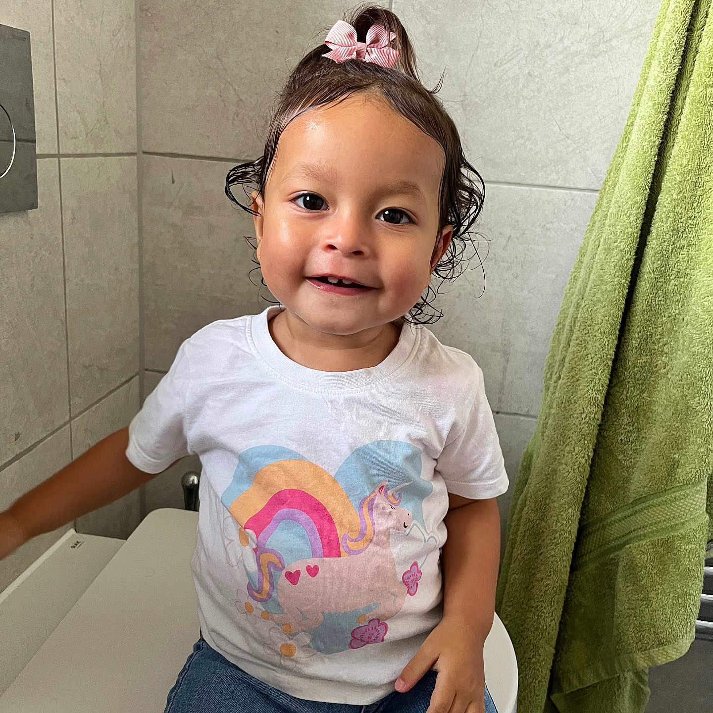 Yarin joined the competition — help win amazing prizes! bathroom, casual_clothing, child, cute, green_towel, happy, indoor, jeans, person, pink_bow, portrait, rainbow, sitting, smiling, tiled_wall, toddler, toilet, unicorn, wet_hair, white_tshirt