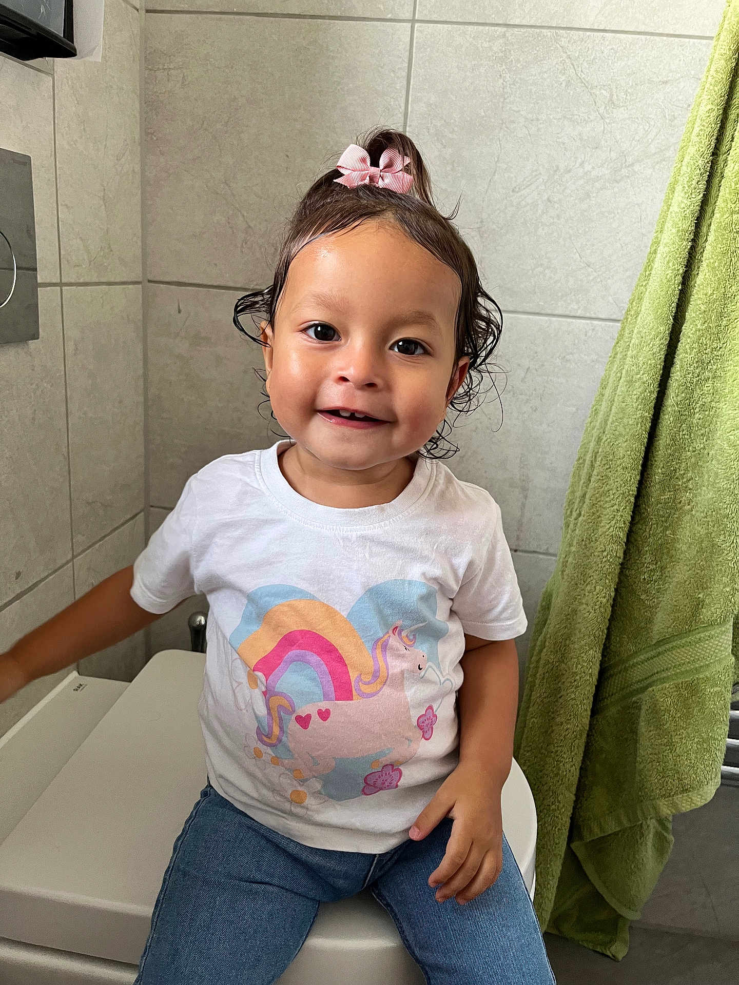 Yarin joined the competition — help win amazing prizes! bathroom, casual_clothing, child, cute, green_towel, happy, indoor, jeans, person, pink_bow, portrait, rainbow, sitting, smiling, tiled_wall, toddler, toilet, unicorn, wet_hair, white_tshirt