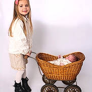 Mia participe au concours pour gagner de l'argent avec cette photo : baby, basket, big_sister, boots, child, clothing, cute, flower_hairclip, hands, indoor, long_hair, newborn, portrait, sibling, smile, standing, studio_portrait, vintage_wheels, white_background, wicker_pram