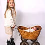 baby, basket, big_sister, boots, child, clothing, cute, flower_hairclip, hands, indoor, long_hair, newborn, portrait, sibling, smile, standing, studio_portrait, vintage_wheels, white_background, wicker_pram