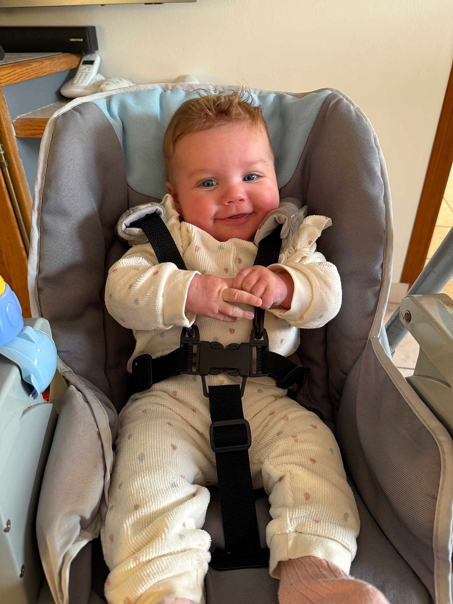 Léna a rejoint le concours — aidez-le/la à gagner de superbes lots ! baby, child, smiling, seat, baby_seat, straps, clothing, pajamas, indoor, person, cute, infant, happy, face, hands, footwear, pink_socks, wooden_furniture, telecommunication_device, home