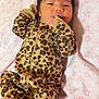baby, infant, leopard_print, onesie, blanket, pink, stars, hand, lying_down, cute, face, person, child, newborn, pattern, sleepwear, soft, cozy, indoor, portrait