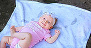 Ember joined the competition — help win amazing prizes! baby, infant, pink_onesie, headband, white_blanket, smiling, outdoor, playful, cute, child, young, lying_down, happy, skin, face, foot, hand, head, person, baby_girl