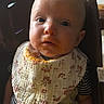 baby, child, face, bib, messy_face, high_chair, indoor, clothing, striped_shirt, expression, young_child, person, infant, cute, portrait, feeding_time, messy, seated, looking_up, close_up