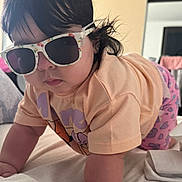 Chloe is registered to the contest to win money with this photo: baby, bed, child, clothing, crawling, cute, face, funny, glasses, hair, hand, indoor, patterned_pants, person, pink, portrait, short_sleeve, skin, sunglasses, toddler