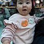 baby, casual_clothing, child, curious, cute, expression, face, fashion, ghost_patch, hands, holding, indoor, long_hair, people, person, pink_bow, pink_sweatshirt, pumpkin_patch, shopping_mall, toddler