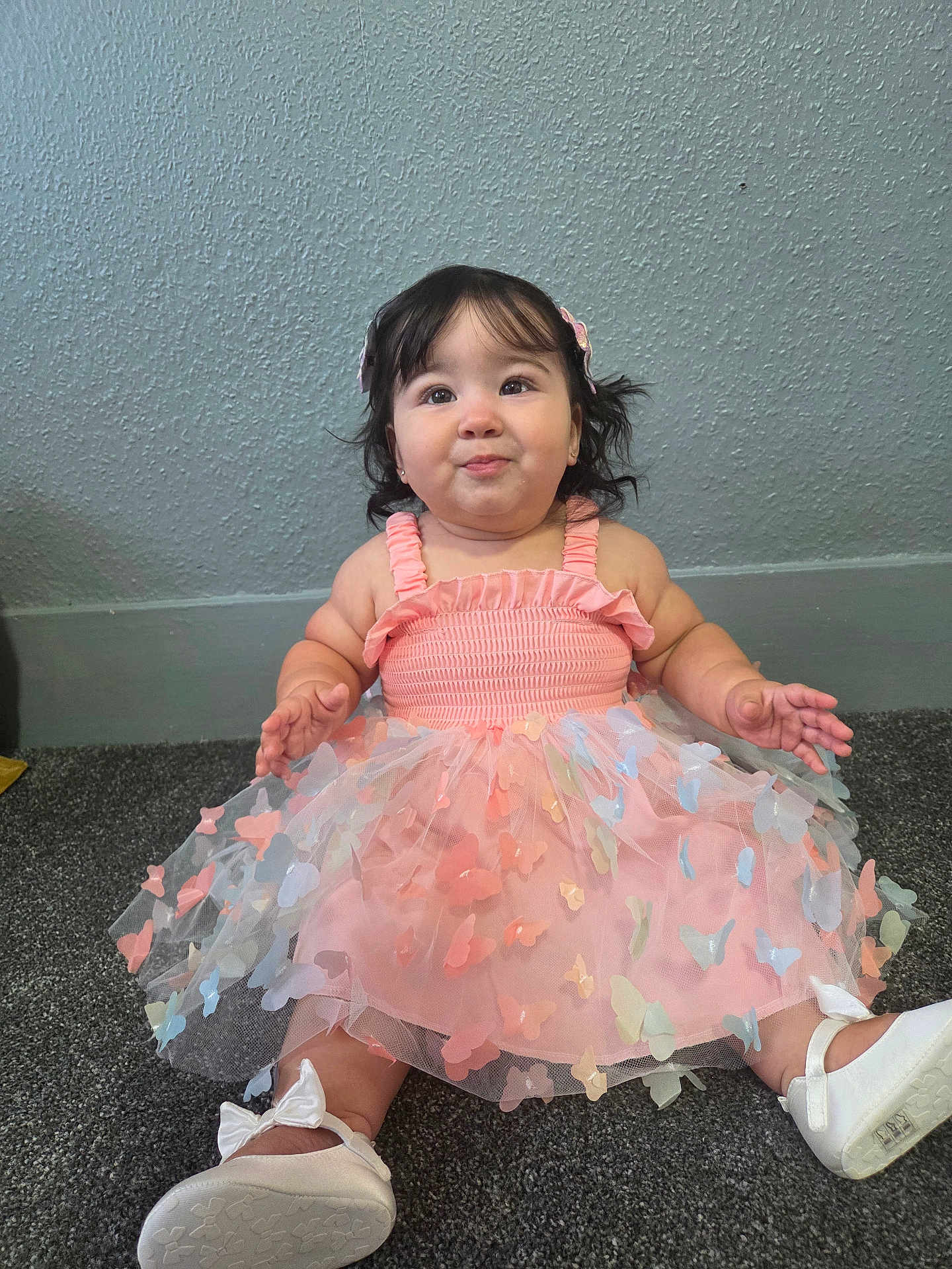 Chloe joined the competition — help win amazing prizes! baby, child, girl, dress, pink, butterflies, carpet, white_shoes, bows, indoor, portrait, cute, smiling, happy, sitting, hair_clip, curly_hair, wall, floor, young