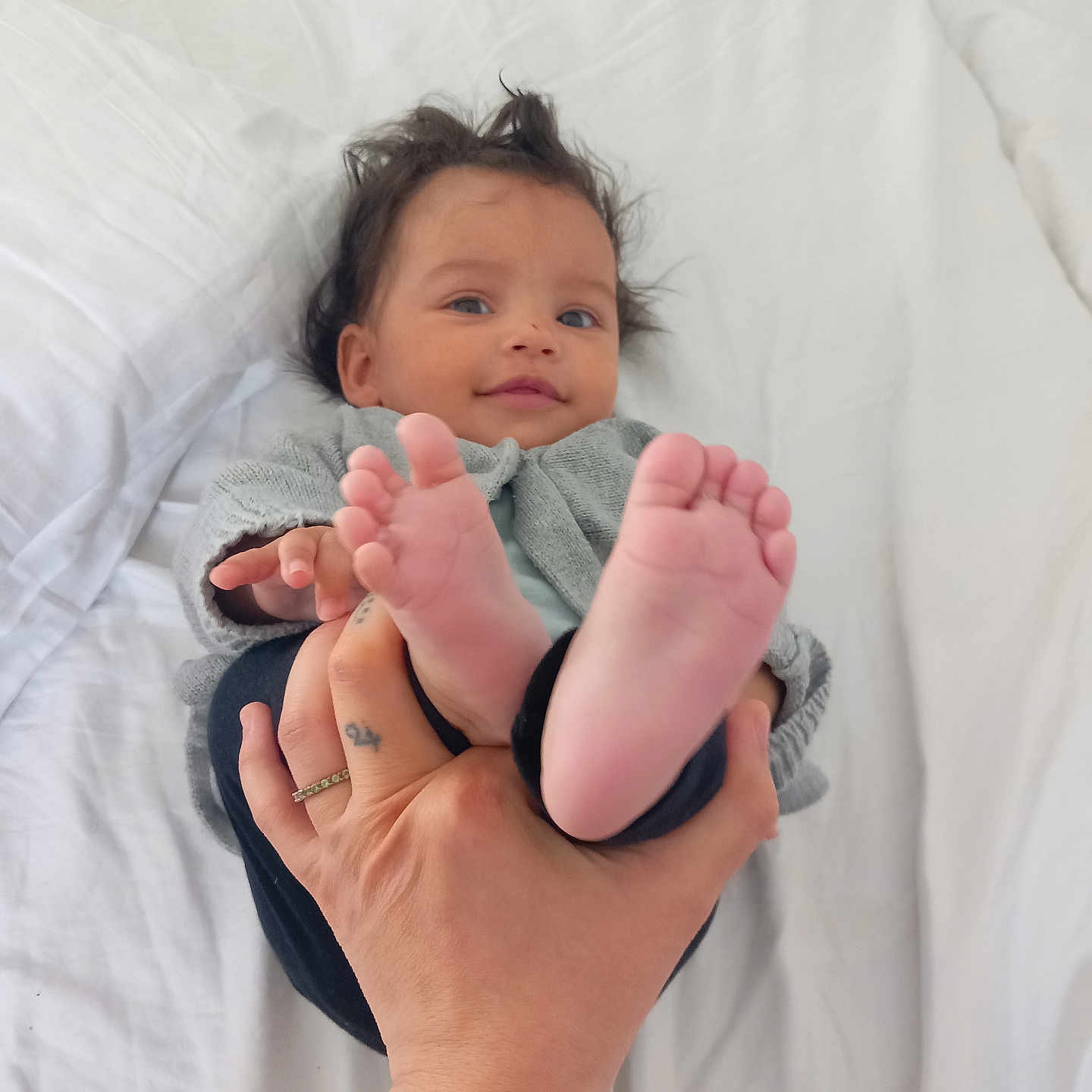 Seeyana participe au concours pour gagner de l'argent avec cette photo : baby, bed, blanket, child, clothing, cute, face, feet, hair, hand, happy, infant, person, playful, portrait, skin, sleeve, smile, tattoo, white