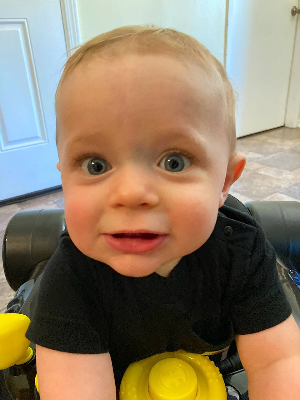 Rogan is registered to the contest to win money with this photo: baby, baby_playing_with_toys, cheek, child, chin, door, eye, facial_expression, finger, flooring, fun, hairstyle, happy, iris, mouth, nose, person, skin, smile, toddler