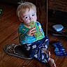 Kelver is registered to the contest to win money with this photo: toddler, child, floor, wooden_floor, slippers, bottle, sitting, indoor, blue_pants, long_sleeve_shirt, snack_bag, living_room, furniture, table, couch, barefoot, blond_hair, cute, drinking, casual