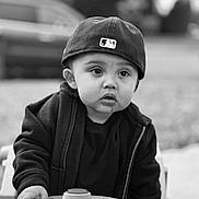 Christopher joined the competition — help win amazing prizes! baseball_cap, black_and_white, boy, cap, child, clothing, curious, cute, expression, face, hand, jacket, outdoor, person, playing, portrait, steering_wheel, toddler, toy_car, young