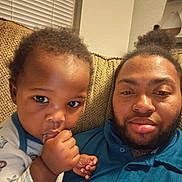 Landon is registered to the contest to win money with this photo: adult, beard, bonding, casual_clothing, close_up, couch, curly_hair, expression, face, family, hand, home, indoor, portrait, relaxed, seated, skin, thumb_sucking, toddler, window_blinds