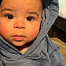 baby, child, infant, portrait, face, eyes, hood, hoodie, gray_clothing, sitting, indoor, close_up, looking_at_camera, cute, calm, photography, head, hair, couch, home