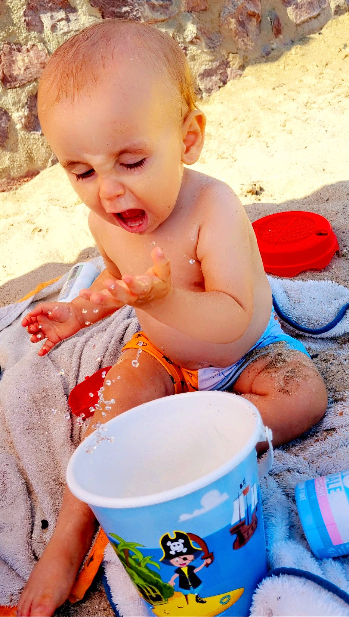 Aaron a rejoint le concours — aidez-le/la à gagner de superbes lots ! baby, baby_toddler_clothing, beach, blue, bucket, child, cup, drinkware, fun, happy, pattern, people, people_in_nature, person, play, sitting, summer, sweetness, toddler, vacation
