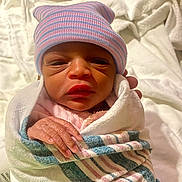 Janiyah joined the competition — help win amazing prizes! newborn, baby, infant, hospital, blanket, hat, striped_hat, wrapped, sleepy, hand, skin, person, portrait, cute, small, resting, indoors, cloth, headwear, human
