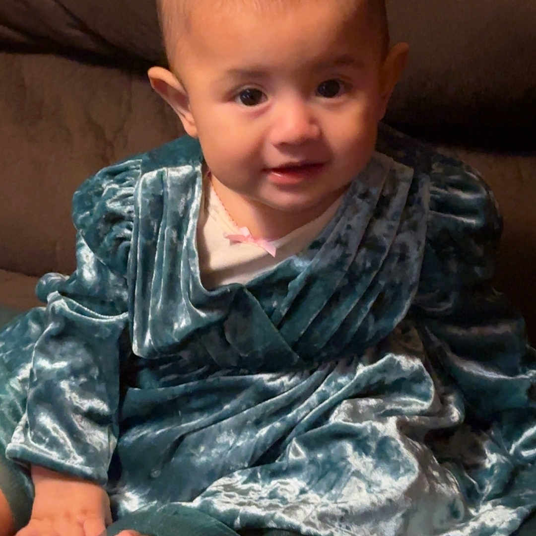 María Victoria joined the competition — help win amazing prizes! baby, blue_dress, child, couch, cozy, cute, face, fashion, feet, hands, happy, indoor, infant, person, portrait, sitting, smile, soft_lighting, velvet_dress, young_child