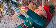 Casper joined the competition — help win amazing prizes! baby, celebration, child, christmas_tree, cute, decorations, elf_costume, exploring, festive, frosted_branches, holiday, holiday_season, indoor, infant, knitted_blanket, lights, ornament, reaching, striped_pants, winter