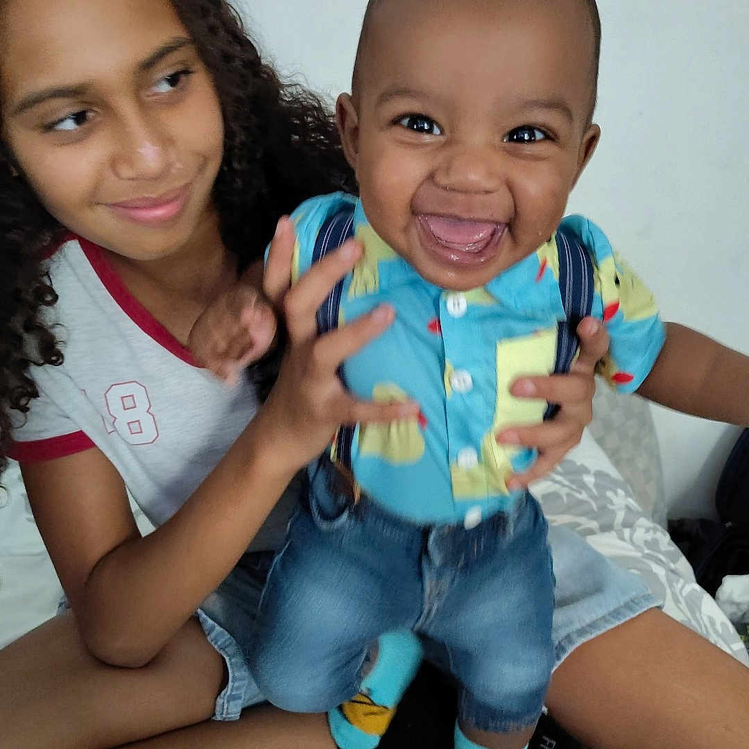 Avaughn is registered to the contest to win money with this photo: baby, bed, casual, child, clothing, curly_hair, cute, denim_shorts, fun, happy, holding, indoor, patterned_bedspread, person, playing, portrait, sibling, smile, socks, toddler