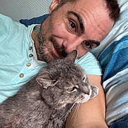 Fanette participe au concours pour gagner de l'argent avec cette photo : animal, bed, casual_clothing, cat, comfort, cozy, cute, facial_hair, friendship, gray_cat, human, indoor, man, pet, portrait, relaxing, selfie, short_hair, smile, striped_bedding