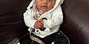 Heaven is registered to the contest to win money with this photo: baby, child, infant, face, headband, clothing, jacket, pants, socks, couch, leather, indoors, pacifier_clip, seated, expression, cute, bundle, comfort, young, portrait